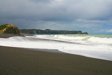 Whirinaki beach near Napier. Dark volcanic stone sand on a black sandy beach with huge Pacific Ocean waves, Hawke's Bay, Napier, North Island, New Zealand