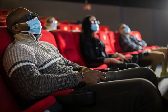 People sit in the cinema hall and watch a movie wearing medical masks and keep their distance. Covid-19 and the film industry