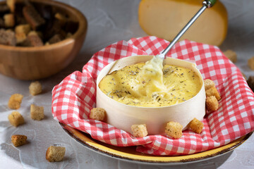 Camembert or brie circle cheese in box with croutons. Cow's milk soft fatty cheese.Cheese fondue.