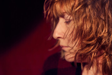 Portrait of tousled disheveled middle-aged woman on red background. Unprofessional female model in the Studio.