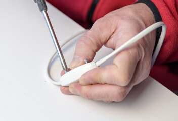 Home hobby. Close-up of a Caucasian man holding a screwdriver, working on an electrician's plug on a white background. switch boron.