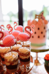 birthday exitic catering, table with modern desserts, cupcakes, sweets with flamingo. delicious candy bar at expensive birthday party. space for text. baby shower. holiday celebration