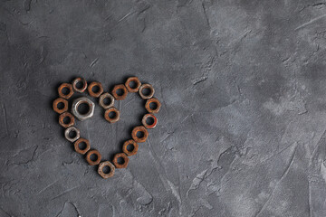 Heart made of small rusty nuts. Machine parts. Items on a dark background.