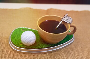 Golf ball with cup of coffee on green grass