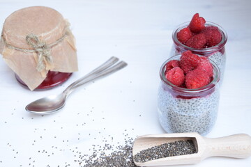 Chia seed pudding, super food healthy chia dessert with raspberries on white wooden background