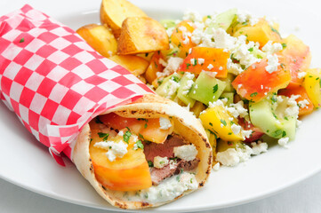 pork pita wrap and side salad and potatoes, fresh heirloom toma