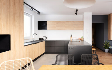 Luxurious kitchen in apartment with kitchen island, granite counter and woooden cupboard and floor. Exclusive space with stylish chairs and furniture. Bright home.