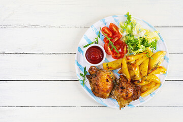Delicious baked chicken with potatoes on wooden background. Top view
