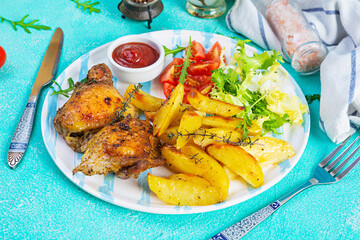 Delicious baked chicken with potatoes on blue background