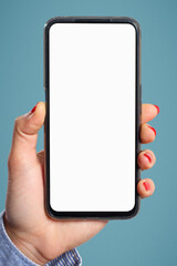 A woman's hand holds vertically a smartphone with a blank white screen on a blue background.