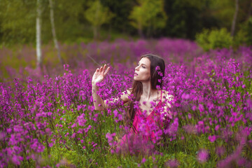 
Girl with a bouquet of flowers, green meadow, purple and pink flowers