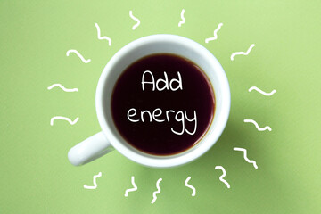 Black coffee in a white cup isolated on a light green background. Inscription Add energy. Top view