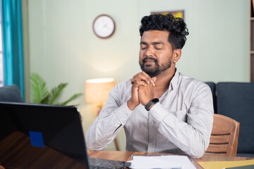 young man praying infront of laptop after complition of online test or examination for results -...