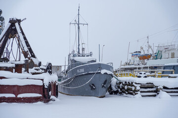 Ships at the winter anchorage in the port. The water is frozen. Front view of the ship.