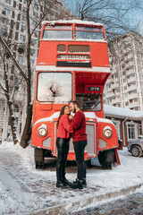 A loving couple hugs on the background of a red bus. Valentine's Day