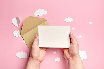 Obraz premium Greeting card mockup in female hands with paper decorations on pink background