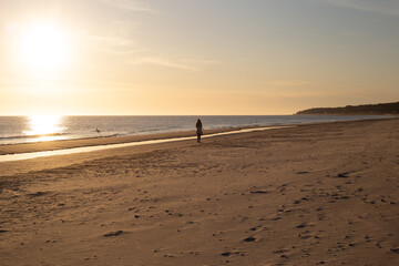 Sonnenaufgang an der Ostsee Frau spaziert am Strand entlang