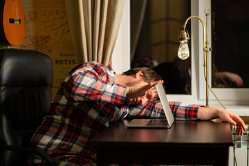 Naklejka premium a man in red plaid pajamas worked late at the computer and fell asleep.
