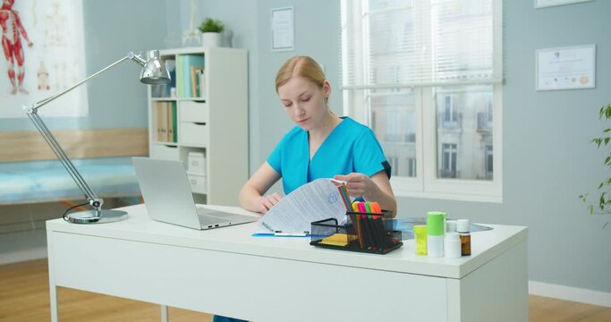 Good-looking female nurse documenting report from papers on clipboard to laptop. Young Caucasian woman checking analysis results and filling out on computer. Technology, digitalization concept.