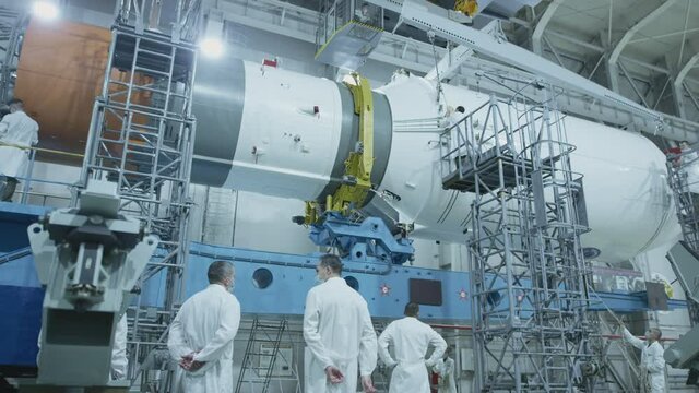 Two scientist engineers inspect the spacecraft, write on the tablet. A space rocket in a military hangar being prepared for launch. Space technologies. Construction of Big Rocket. Humanity in Space