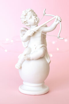 figurine of an angel Cupid with a bow on a pink background. Valentine's Day.