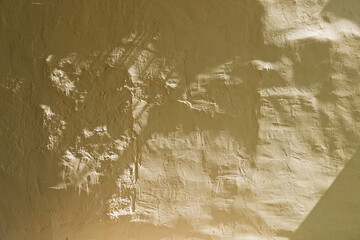 painted yellow plastered uneven wall in the sun