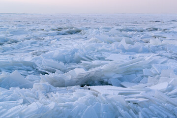 Obraz premium Many pieces of ice covered with white snow on a re-frozen body of water. Winter in Eastern Europe. Landscape. Horizontal orientation.