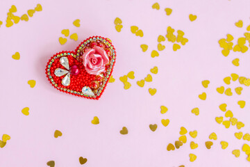 Pink background with gold hearts, sequins. Red heart made of beads. The concept of the Valentine's Day theme. Postcard, template, background for graphic works. 