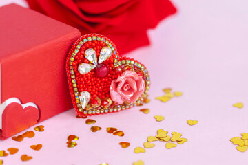 Pink background with gold hearts, sequins. Red heart made of beads. The concept of the Valentine's Day theme. Postcard, template, background for graphic works. 