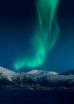 Northern lights above snow covered mountains and the Town of Narvik in Norway