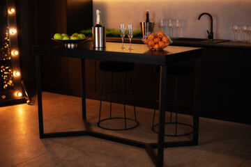 Modern kitchen interior in a loft style in dark colors. Stylish modern kitchen area with an island. Champagne bottle in bucket with ice and glasses of Champagne on kitchen island. celebration concept
