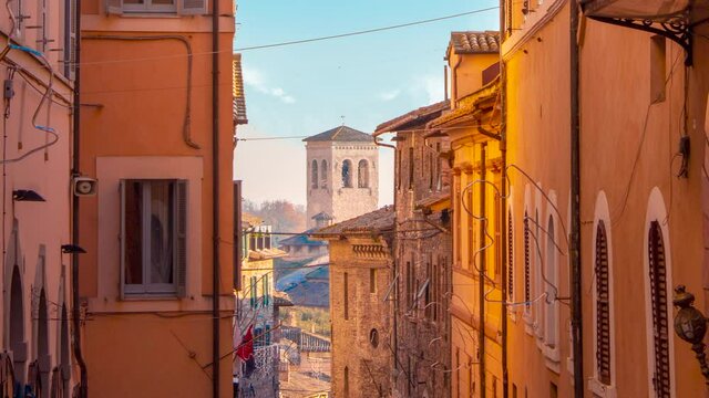 time lapse of medieval stone old town of Assisi in province of Umbria, italy at sunset  with clear cloudy sky and medieval tower  in background