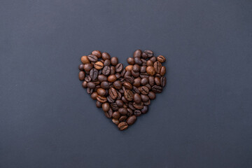 a photo of coffee beans arranged in a heart of Valentine's Day on a dark background