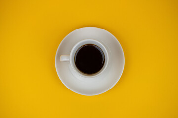 a photo with selective focus with a cup of coffee on a yellow background