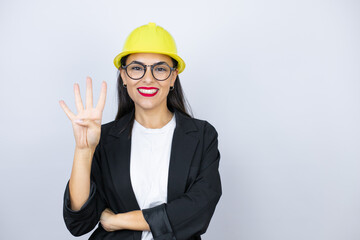 Young architect woman wearing hardhat showing and pointing up with fingers number four while smiling confident and happy