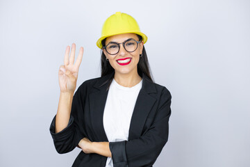 Young architect woman wearing hardhat showing and pointing up with fingers number three while smiling confident and happy