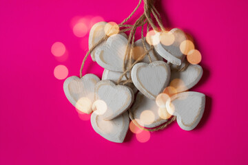 Group of hearts carved and made of chipped wood on a pink background with natural light. Unfiltered romantic image, full of love for Valentine's Day.