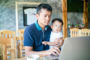 Busy father working on laptop business communication hold with baby boy annoy