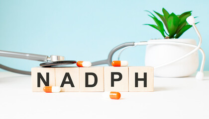 The word NADPH is written on wooden cubes near a stethoscope on a wooden background. Medical concept