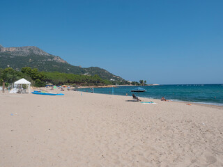 Santa Maria Navarrese, Sardinia, Italy, September 18, 2020: Sand beach Spiaggia di Santa Maria Navarrese with few sunbathing people and view of green hill of Monte Oro. Summer sunny day