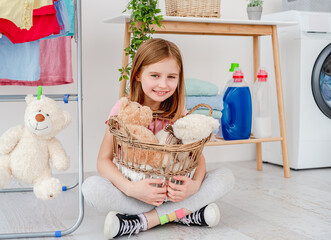 Little girl holding toys in washing basket
