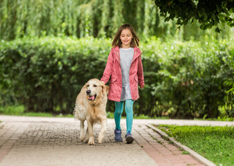 Little girl with dog going along alley
