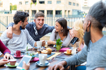 group of multiethnic friends on coffee break, college students having breakfast with cups of tea, chocolate muffins and different kinds of coffee drinks, socialization in covid outbreak with masks