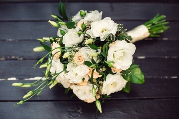 The wedding bouquet is lying on a black bench. Pastel colors.