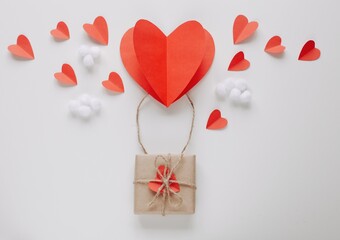 Flat lay Happy Valentine's Day photography with gift box and paper origami heart in air balloon shape. Cute romantic greeting card. 