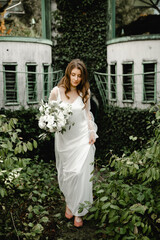 lovely young bride walks with a bouquet of flowers along the footpath in the botanical garden. floristry of a wedding bouquet. festive white flowers. Wedding Dress. beautiful modern dress.