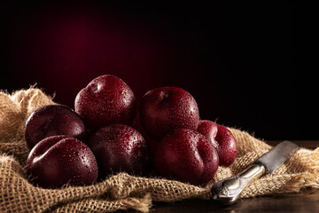 Ripe plums on wooden table and jute