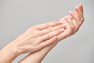 Beautiful Female Hands with French manicure over light grey background
