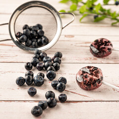 Homemade lollipops made from natural dehydrated bilberry on a white wooden background. Healthy vegan vegetarian food with no sweets.