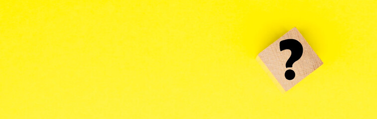 Wooden cube block shape with sign question mark symbol on yellow. FAQ frequency asked questions,...